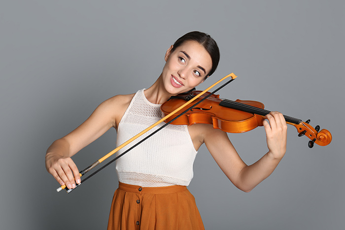 Adult violinist practising bow control and straight bow technique against a neutral studio background
